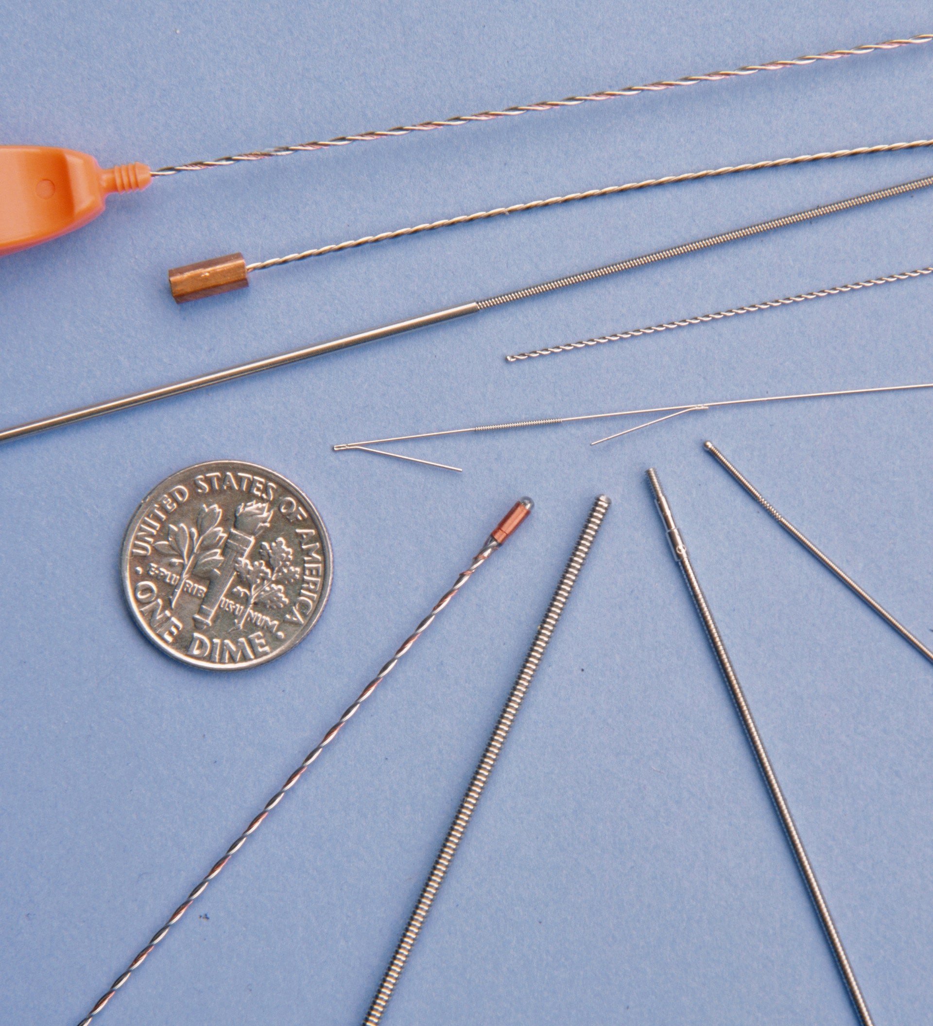 Assorted wire medical products scale compared to a dime